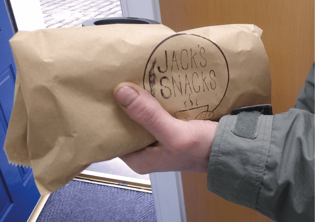 A close up photo of someone holding a sandwich in a Jack's Snacks bag